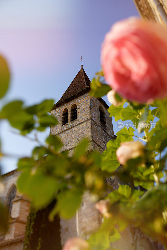法国新阿基坦省多尔多涅美丽的小村庄，夏天前景中有玫瑰的蒙帕齐耶教堂