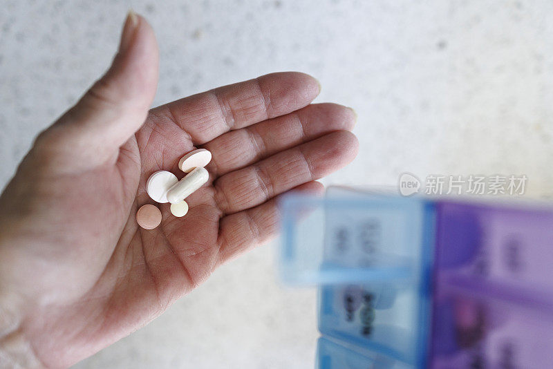 药片计划者:一位老人从她每周的药物计划者手中拿着药片。