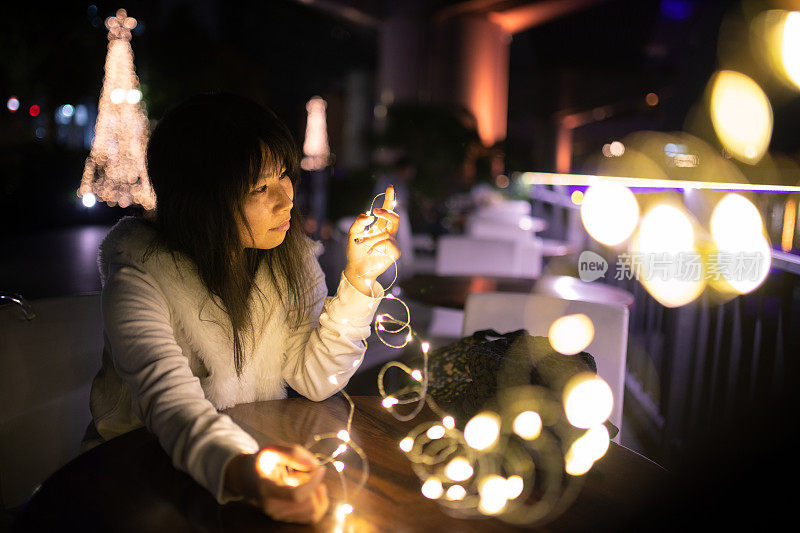 一个女人在露天咖啡馆玩圣诞彩灯