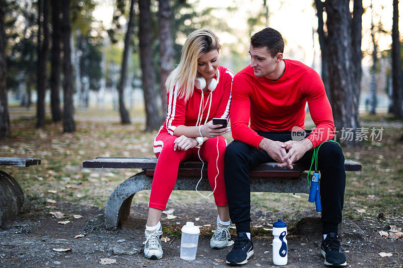 年轻的运动夫妇在秋季运动后使用智能手机