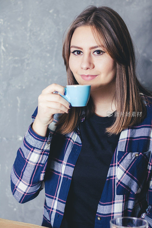 年轻的白人妇女捧着一杯咖啡享受在自由时间的肖像。