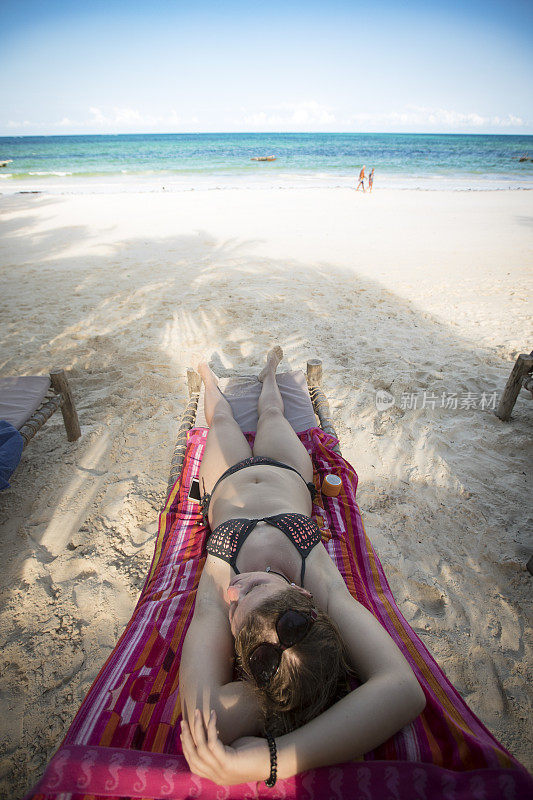年轻女子在沙滩上的躺椅上休息