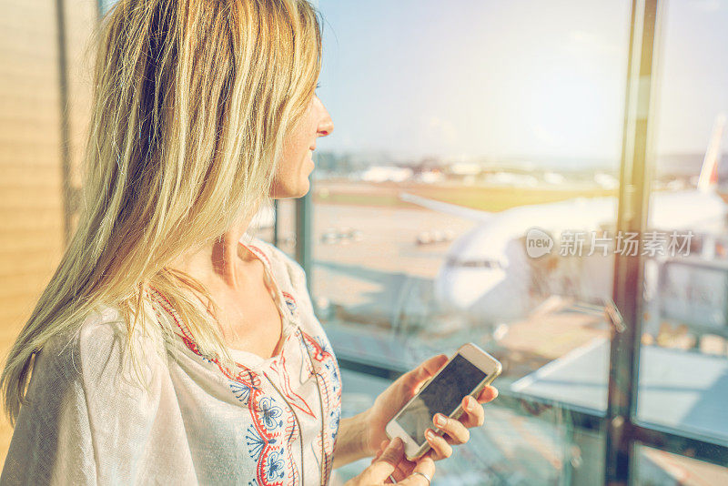 一名年轻女子在机场用手机发短信