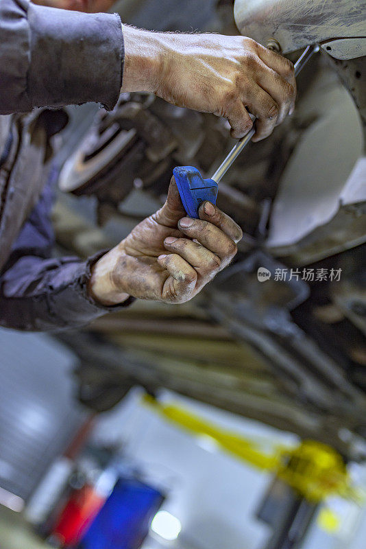 一名男性机械师在汽车下面工作的照片