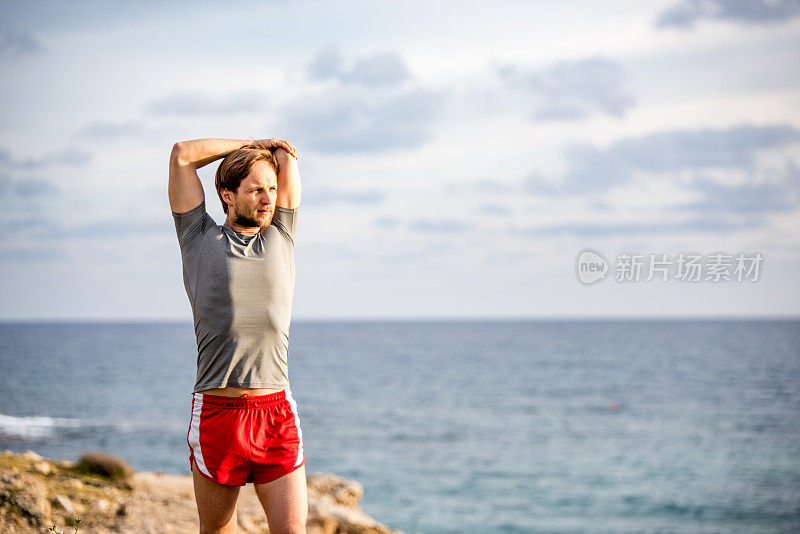 年轻的男运动员在塞浦路斯岛上的海边跑步。