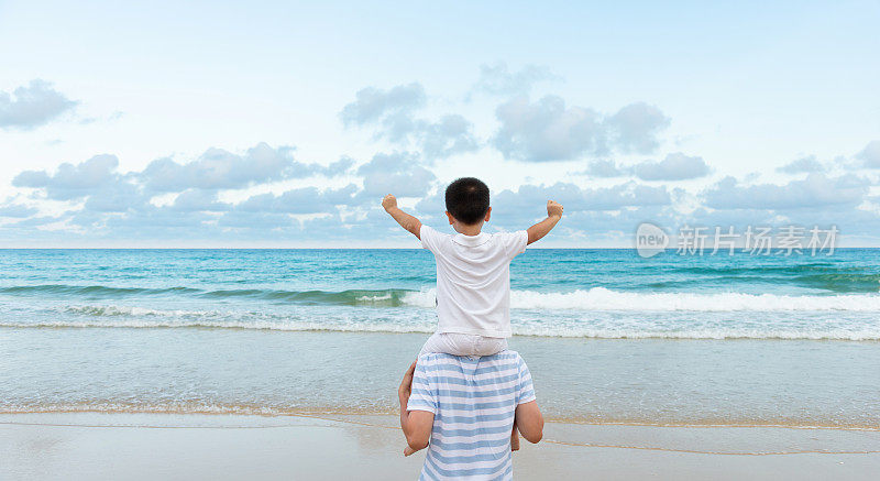 儿子坐在父亲的肩膀上享受海滩