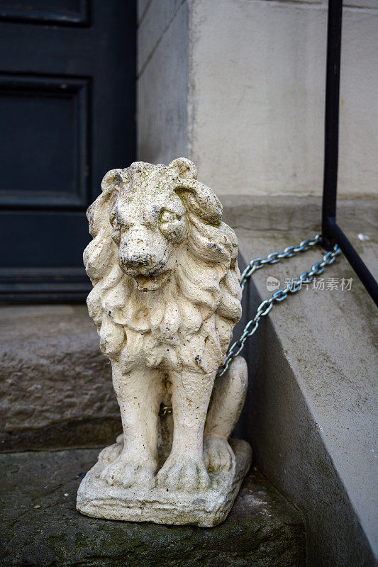 德国吕贝克老城，用石头或石膏制成的狮子雕像被拴在一所房子的入口处