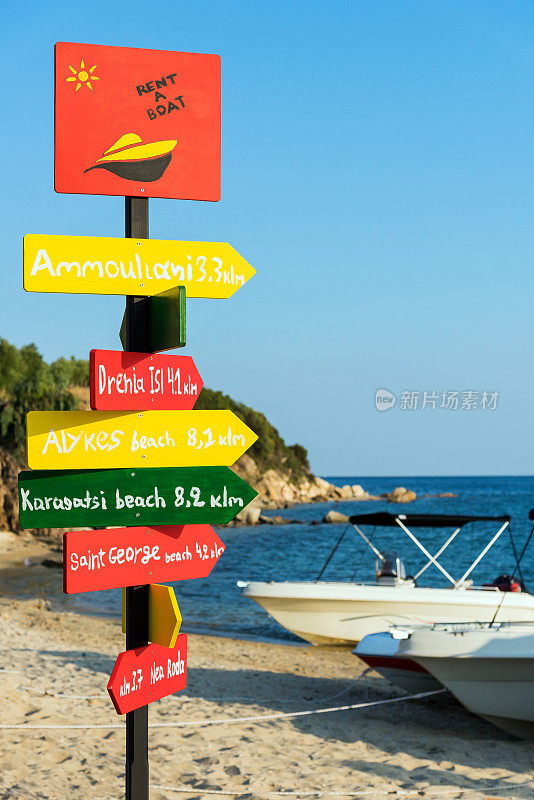 希腊哈尔基迪基，落日时分，沙滩上并排站着五颜六色的路标和出租船