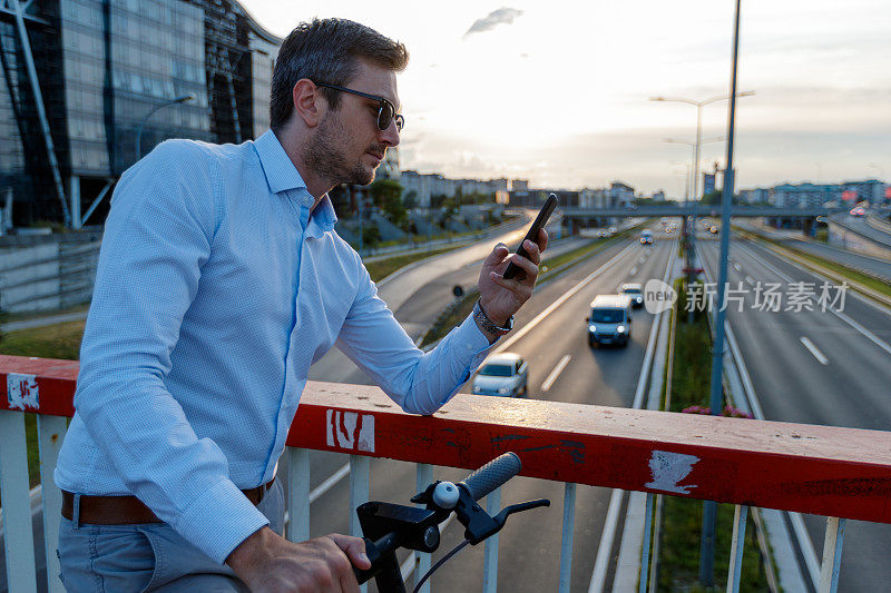 通勤者靠在高速公路上方的高架道路围栏上发短信