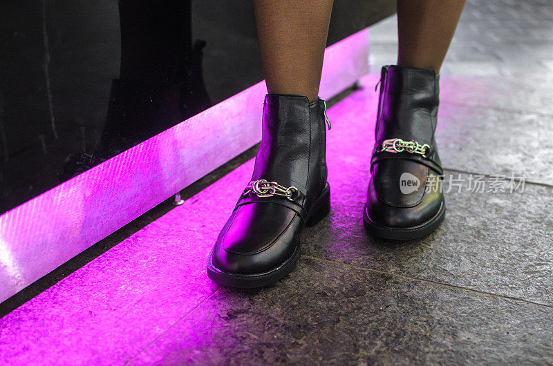 一个女孩穿着时尚的黑色鞋子，在一家购物中心附近紫光闪烁，靓丽的照片