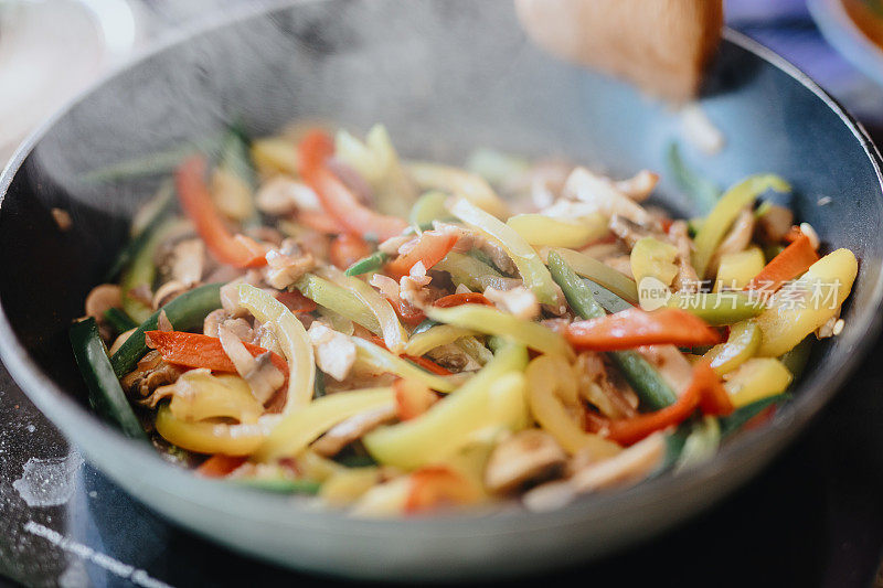 厨师在煎锅中搅拌蘑菇，jalapeños和洋葱