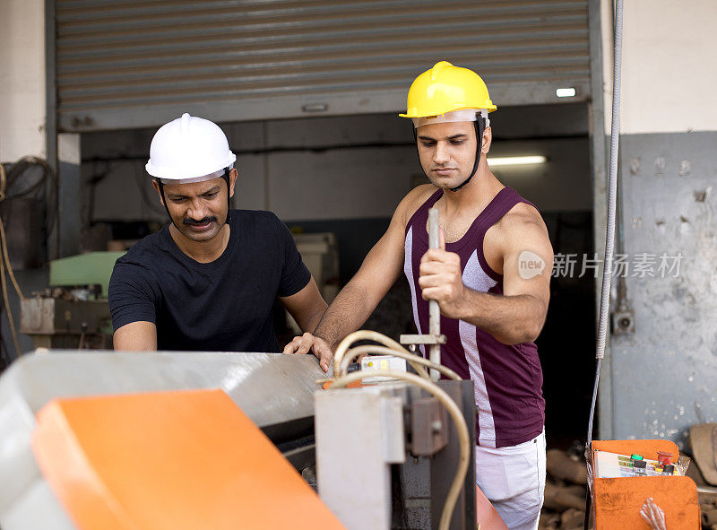 两名男性维修工程师在工厂检查机器