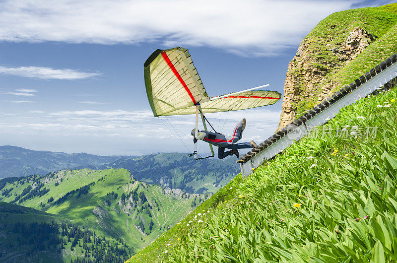 悬挂式滑翔机飞行员在高山的陡坡上飞行。