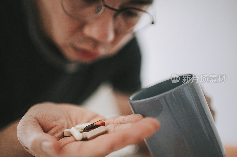 一位患有流感症状的亚洲华人中年男子正在服用以手掌药为主的药丸