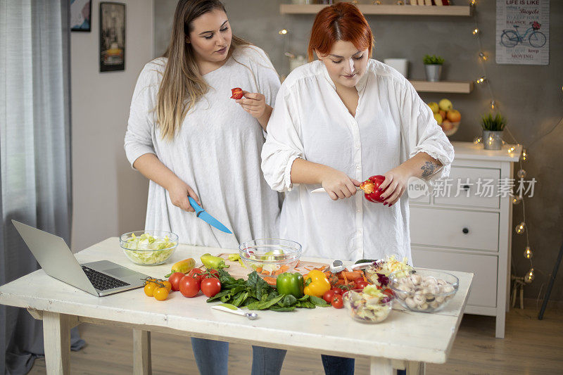 年轻微笑的胖女人用笔记本电脑准备早餐。