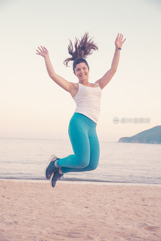 体育训练。年轻女子放松在海边的沙滩上锻炼。健康生活，海滩度假