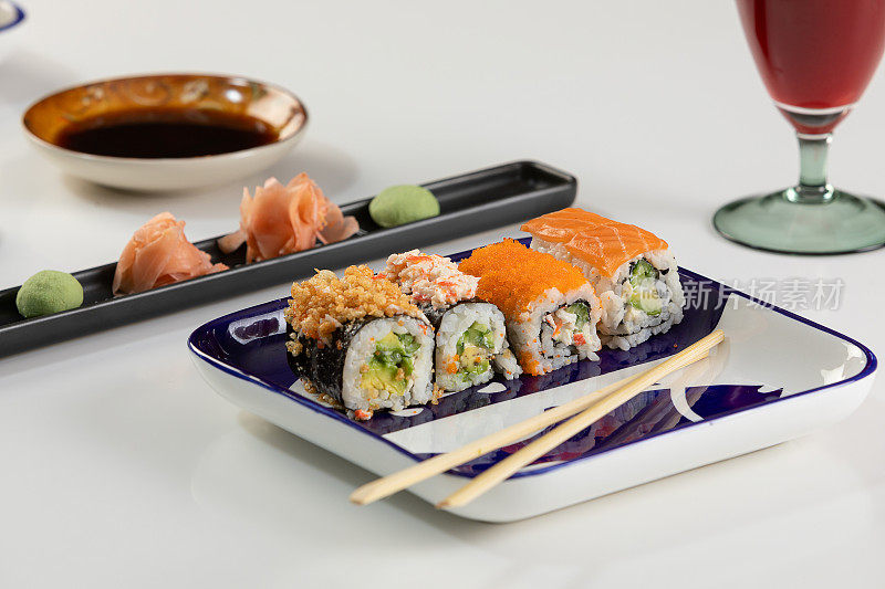 一套寿司和卷三文鱼和金枪鱼，鳄梨，加州，maki，酱油，筷子特写。
