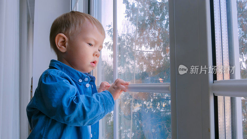 沉思的小男孩望着窗外