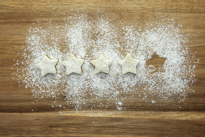 5分中的4分——由糕点星星和糖粉在木质表面上排成一排表示
