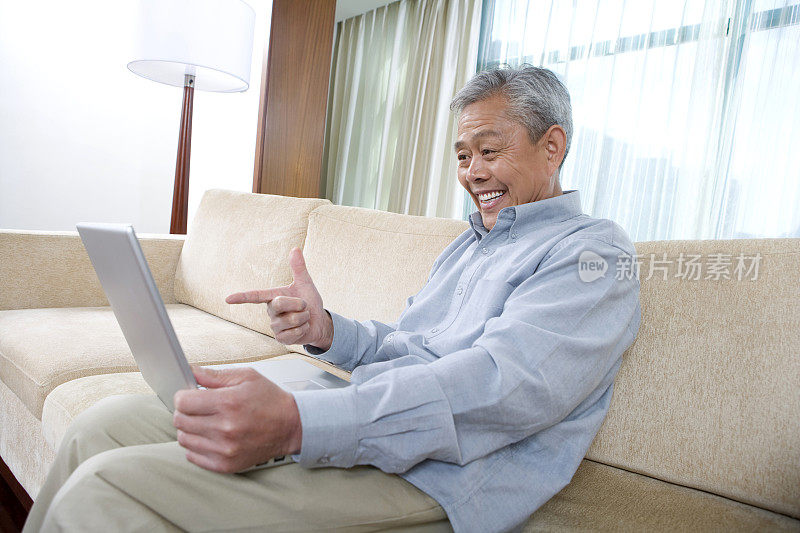 老年人在沙发上用笔记本电脑上网