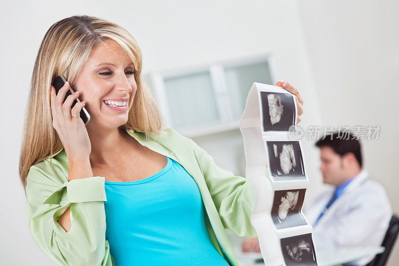 快乐的孕妇妈妈在手机上看超声波图