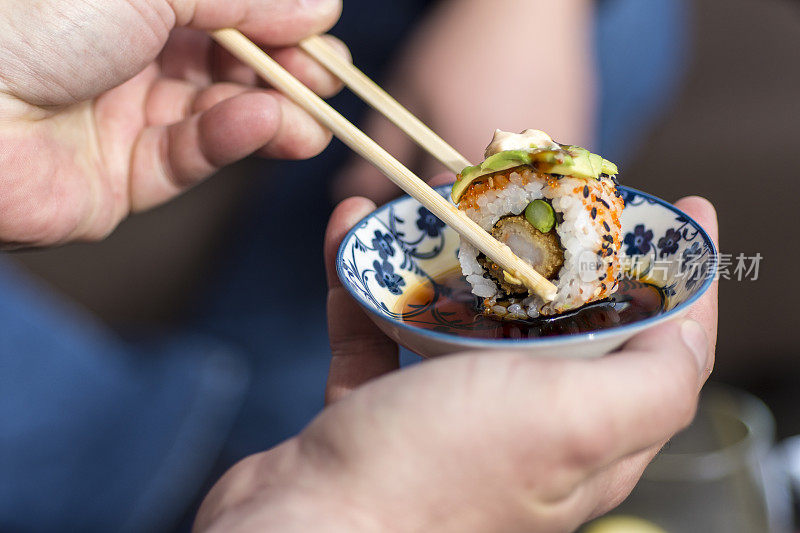 手握筷子蘸寿司卷酱油