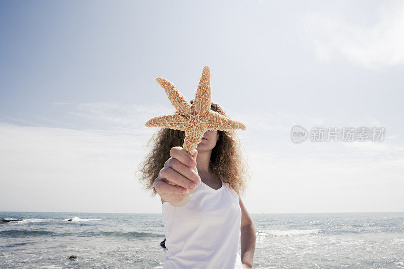 在海滩上抱着海星的女人