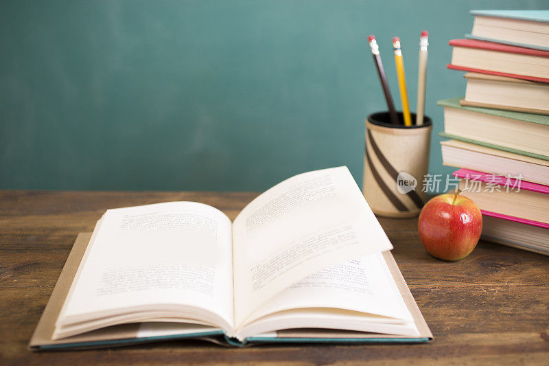用铅笔、苹果和黑板打开课桌上的书。