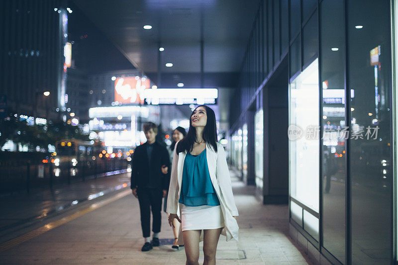 年轻的亚洲女人晚上走在街上