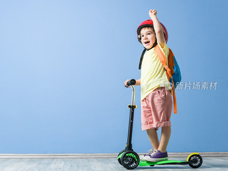 小男孩戴着头盔和他的滑板车摆姿势