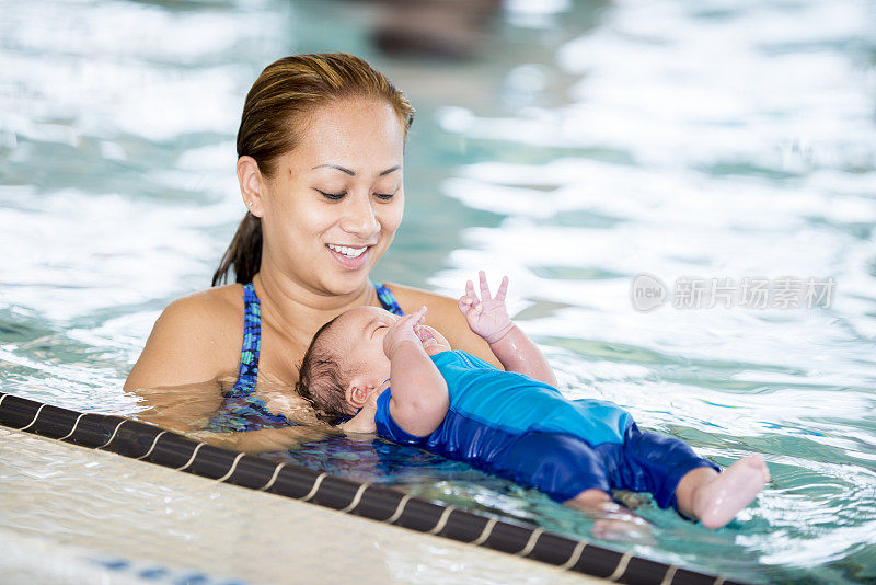 母亲抱着婴儿在游泳池里