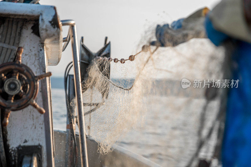 渔民在船上拿着渔网