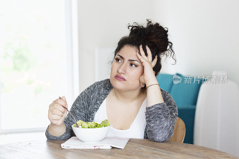 年轻的西班牙妇女饮食吃沙拉不开心