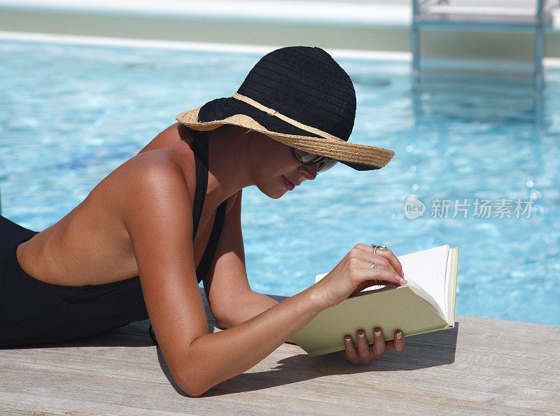 在泳池边看书的女人