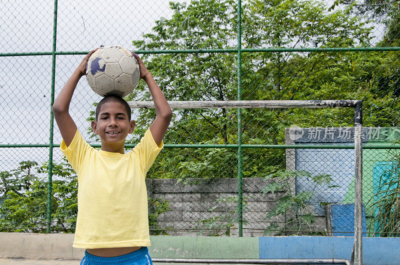 一个巴西男孩拿着足球微笑着，里约热内卢