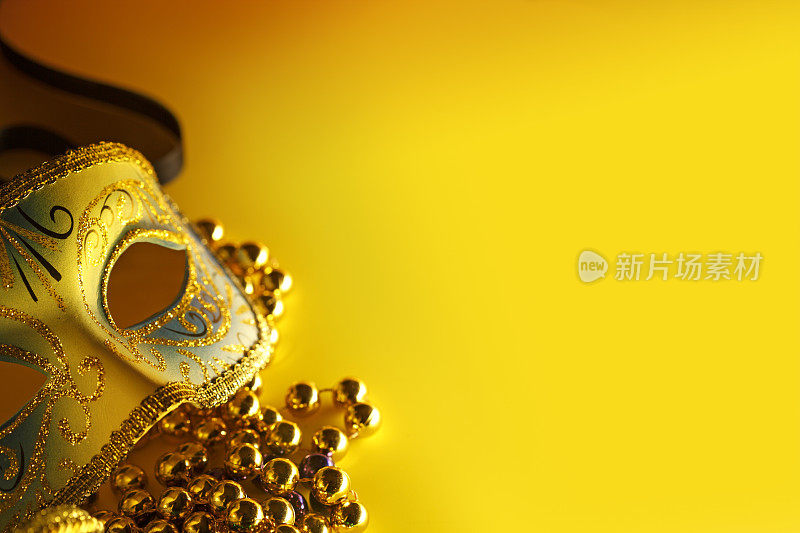 威尼斯面具和黄色背景上的狂欢节珠子
