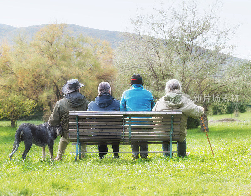 四个老人坐在公园的长椅上