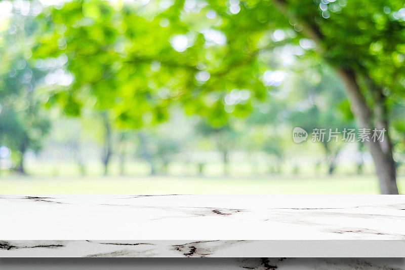 空白的白色大理石桌子上模糊的绿色公园背景，产品显示蒙太奇
