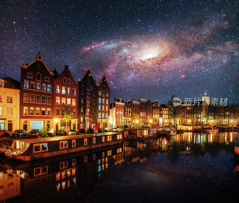 阿姆斯特丹的美丽夜晚。运河水边的建筑物和船只的夜间照明。由美国国家航空航天局