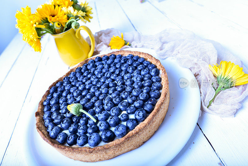 蛋糕和浆果。白色的乡村餐桌上放着夏天盛开的蓝莓派。蓝莓。早餐和早餐概念