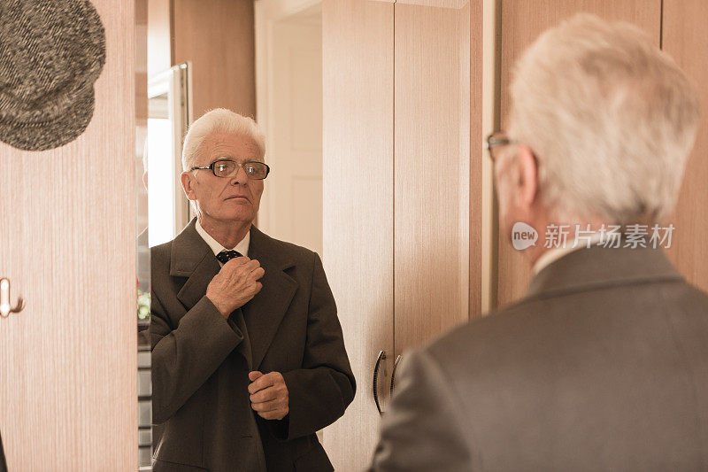 老年人在家里。老男人照镜子，穿衣服，系领带