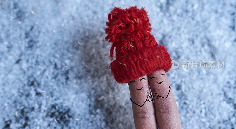 手指艺术的情侣在红帽子在雪的背景