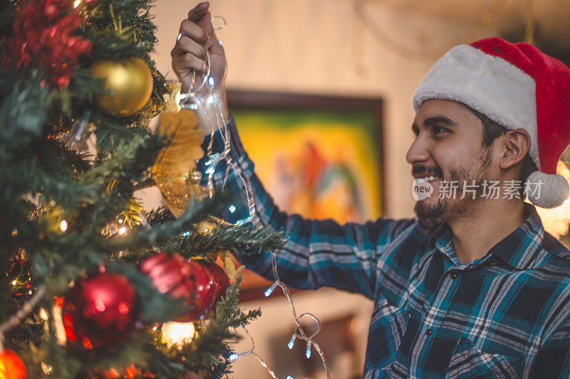 一个年轻人正在帮助装饰圣诞树