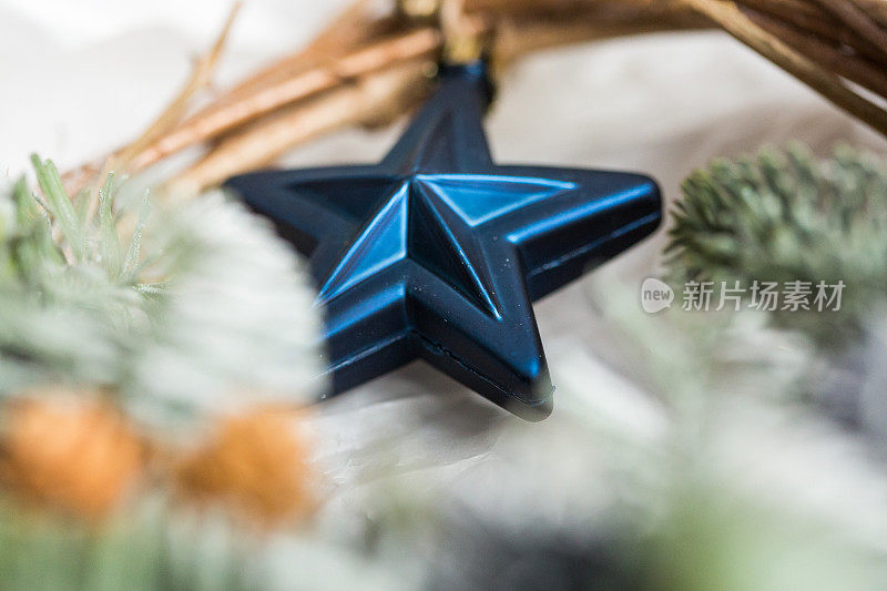 呈现、生活方式、装饰元素概念。近距离的亮蓝色的星星，装饰玩具圣诞树。它在绿枝间闪闪发光