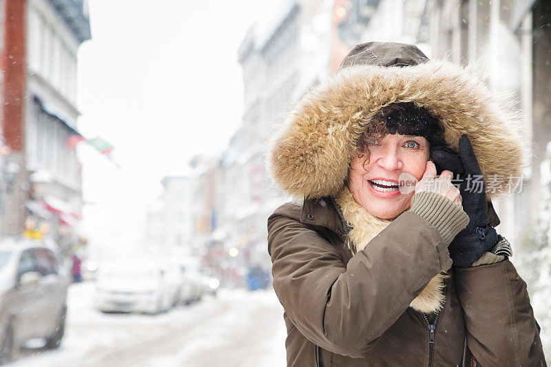 一个成熟的女人在暴风雪天气下在户外打手机