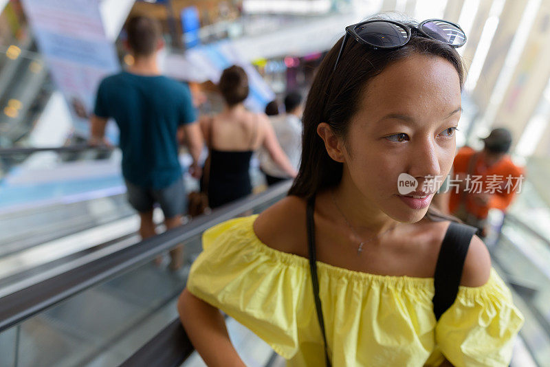 年轻美丽的多民族旅游女人的肖像徘徊在商场在泰国曼谷