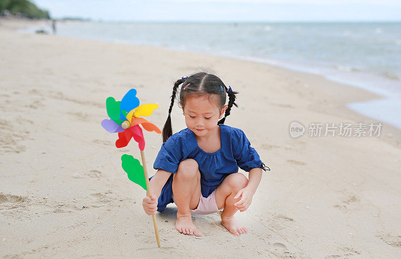 快乐的小女孩拿着风车在海边。