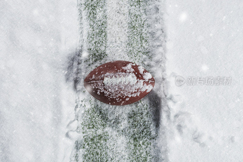 一个美式足球坐在雪地里的院子线上