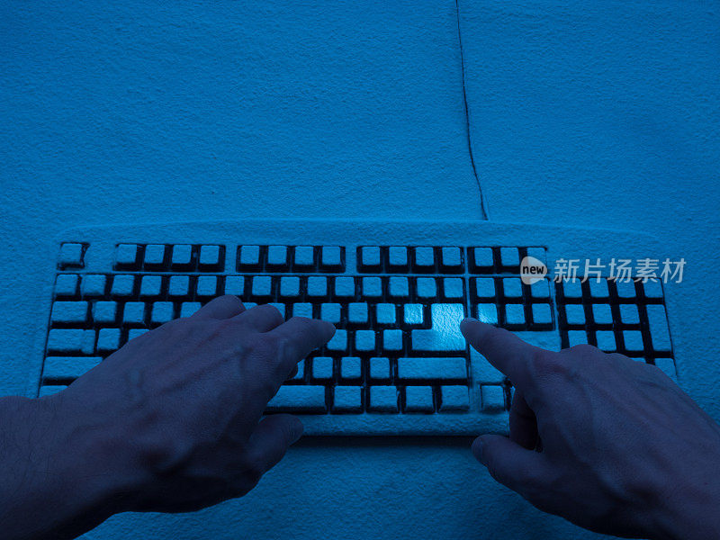 在蓝色霓虹灯的照射下，人们的双手在覆盖着积雪的键盘上打字