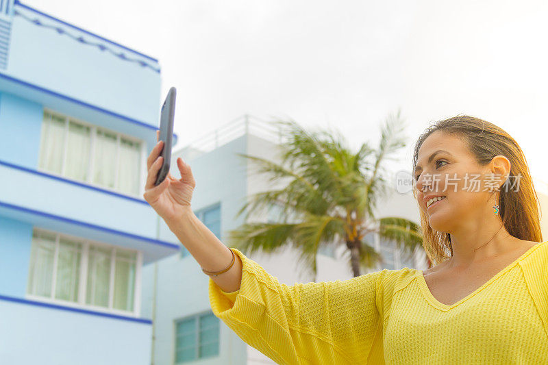 美国佛罗里达州迈阿密海滩，一名年轻女子正在用智能手机拍照